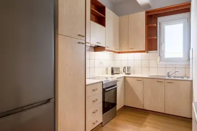 a kitchen with wooden cabinets and a stainless steel refrigerator at Faliro Serenity 2BD Apartment by UPSTREET in Athens