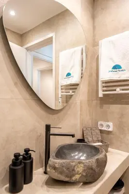 a bathroom with a stone sink and a mirror at Derouse Eva Suite Jacuzzi & Sauna in Athens
