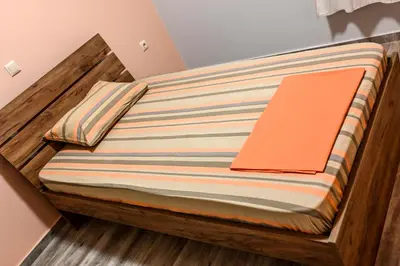 a wooden bed with an orange pillow on it at Marina's dream house in Sounio