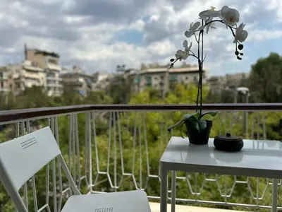 a white table with a flower on a balcony at Koukaki Urban Living Apartment in Athens
