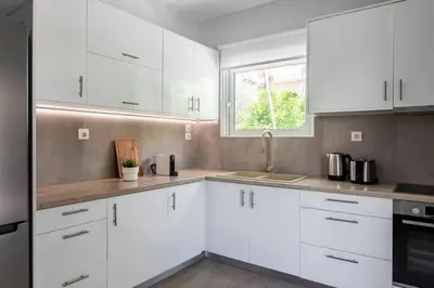 a white kitchen with white cabinets and a window at Faliro Seaside Retreat 2BD Apartment by UPSTREET in Athens