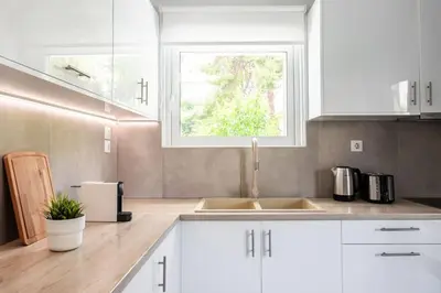 a kitchen with white cabinets and a sink and a window at Faliro Seaside Retreat 2BD Apartment by UPSTREET in Athens