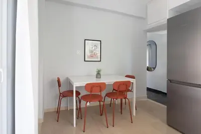 a kitchen with a white table and four red chairs at Faliro Seaside Retreat 2BD Apartment by UPSTREET in Athens