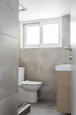 a bathroom with a toilet and a sink and a window at Faliro Seaside Retreat 2BD Apartment by UPSTREET in Athens