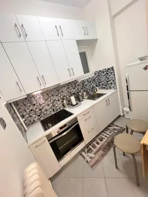 a kitchen with white cabinets and a sink and a refrigerator at Cozy Nest at Lykavitos in Athens