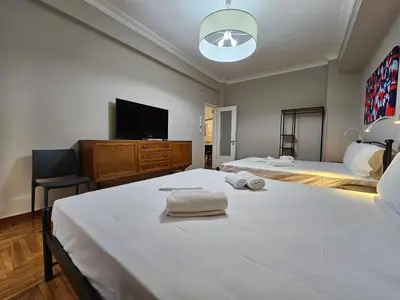 a bedroom with two beds and a flat screen tv at Athens Vibes Apartment by YHA in Athens