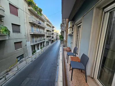 two chairs and a table on a street with buildings at Athens Vibes Apartment by YHA in Athens