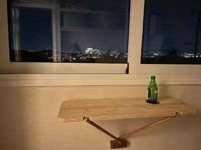 a bottle sitting on a shelf in front of a window at Loft Pagrati in Athens