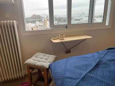 a bedroom with a bed and a stool and windows at Loft Pagrati in Athens