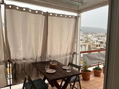 a table on a balcony with a view of a city at Loft Pagrati in Athens