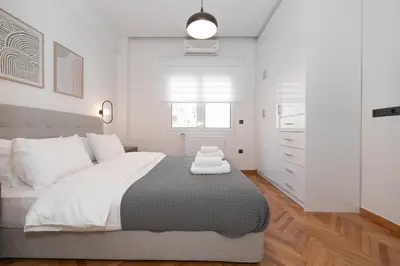 a white bedroom with a large bed and a window at Kolonaki Elegant Apartment with Balcony in Athens