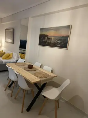 a dining room with a wooden table and white chairs at Luxury 2BR Ellinikon Apartment Oasis - Athens Riviera in Athens