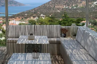 a patio with two tables and a view of the ocean at Hippie Bay Complex in Porto Rafti