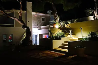 a house with stairs in front of a building at night at Hippie Bay Complex in Porto Rafti