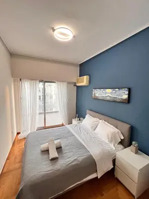 a bedroom with a large bed with a blue wall at Concert Hall Apartment - Semitelou in Athens
