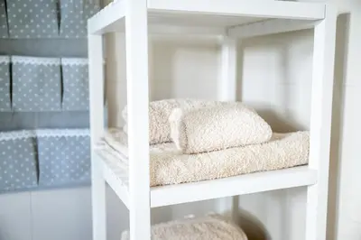 a white shelving unit with towels on it at Sun & Sea Escape Charming Vacation Apartment in Voula on Athen's Riviera in Athens