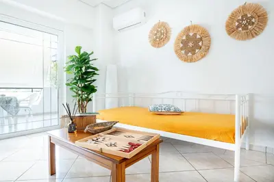 a white bedroom with a bed and a table at Sun & Sea Escape Charming Vacation Apartment in Voula on Athen's Riviera in Athens