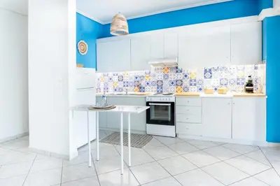 a kitchen with white cabinets and blue walls at Sun & Sea Escape Charming Vacation Apartment in Voula on Athen's Riviera in Athens