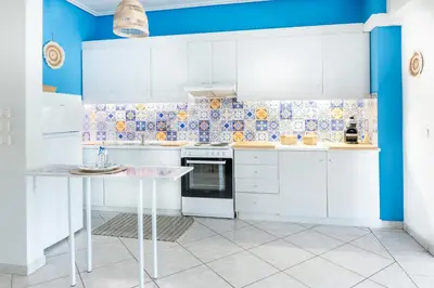 a kitchen with white cabinets and blue walls at Sun & Sea Escape Charming Vacation Apartment in Voula on Athen's Riviera in Athens