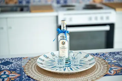 a bottle and two glasses on a plate on a table at Sun & Sea Escape Charming Vacation Apartment in Voula on Athen's Riviera in Athens