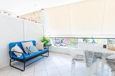 a dining room with a blue chair and a table at Sun & Sea Escape Charming Vacation Apartment in Voula on Athen's Riviera in Athens