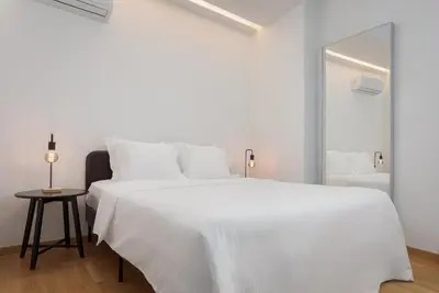 a white bedroom with a large white bed and a mirror at Orpheas Athens Comfy Apartment in Athens