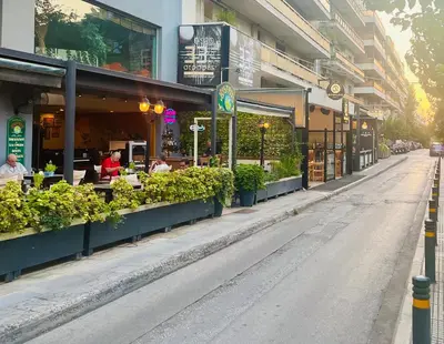an empty street in front of a building with plants at Cosy studio in Pagrati Caravel, 4th floor in Athens