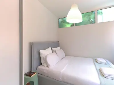 a bed with white sheets and pillows in a room at Cozy Garden Studio in Athens