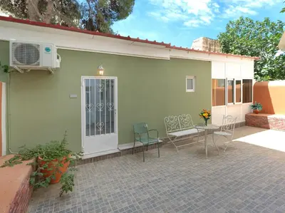 a green house with a patio with chairs and a table at Cozy Garden Studio in Athens