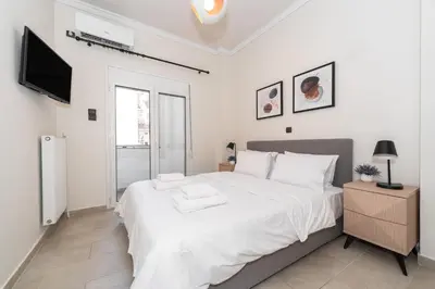 a white bedroom with a large bed and a tv at Modern Apartment in Athens Center, 10 mins walk to Plaka Historical Area in Athens