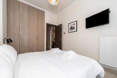 a white bedroom with a white bed and a flat screen tv at Modern Apartment in Athens Center, 10 mins walk to Plaka Historical Area in Athens
