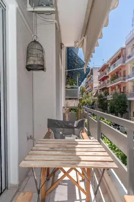 a wooden table on a balcony with a bird cage at Modern Apartment in Athens Center, 10 mins walk to Plaka Historical Area in Athens