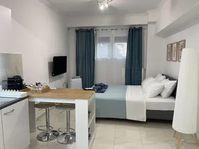 a bedroom with a bed and a kitchen with a table at Zografou City Studio in Athens