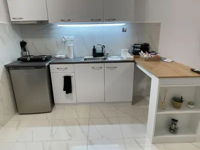 a white kitchen with a sink and a counter at Zografou City Studio in Athens