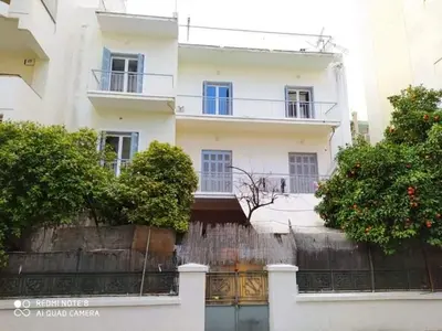 a white building with a fence and trees in front of it at Κρεβάτια σε κοιτώνα 5' from metro in Athens