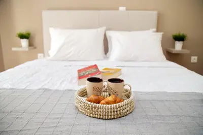 a tray with two cups of coffee and donuts on a bed at Aroura Home 2BR Neos Kosmos in Athens
