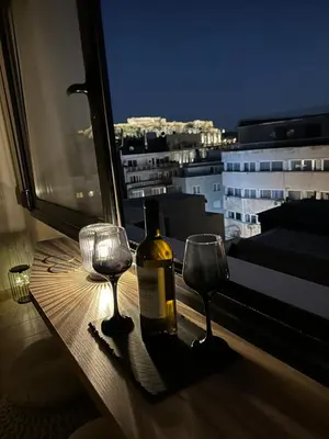 a bottle of wine and two wine glasses on a window at Dionysos Suites in Athens