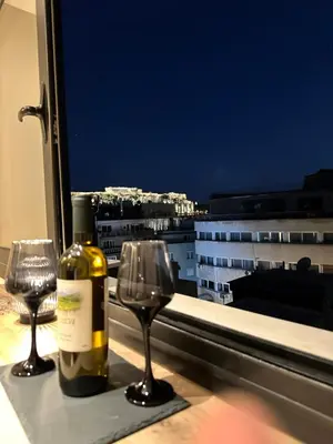 a bottle of wine and two wine glasses in front of a window at Dionysos Suites in Athens