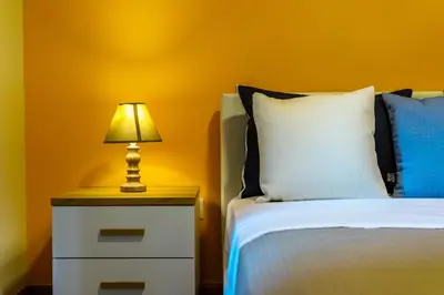 a bed with a nightstand with a lamp on it at Spacious Garden apt in Athens