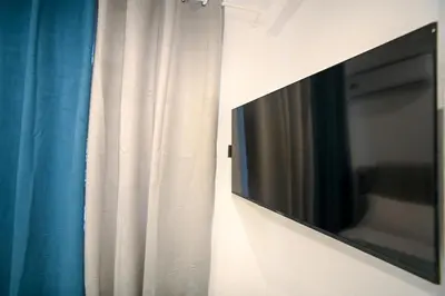 a flat screen tv hanging on a wall next to a curtain at Athinaidos Suite by Zeussuites in Athens