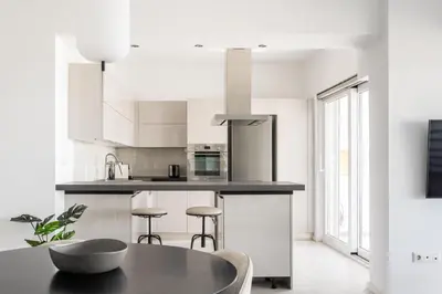 a kitchen with white cabinets and a table and stools at Alimos 2BR Apartment with Splendid Sea View by UPSTREET in Athens