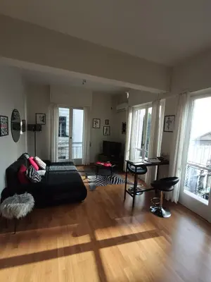 a living room with a black couch and wooden floors at CDV stylish Athens flat in Athens