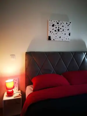 a bedroom with a red bed and a lamp on a table at CDV stylish Athens flat in Athens