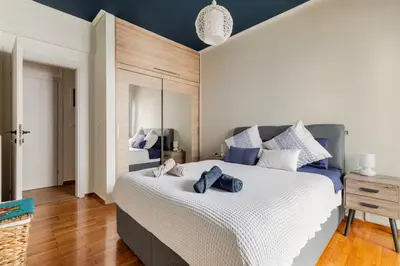 a bedroom with a large white bed with blue accents at Lina's Home in Athens