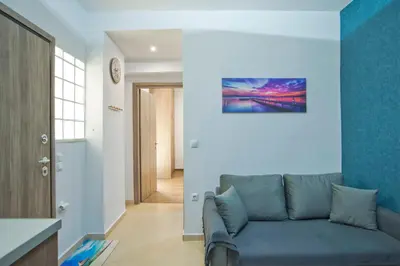 a living room with a couch and a blue wall at Marine Cocoon & Terrace Modern Apt, Private Garden in Athens