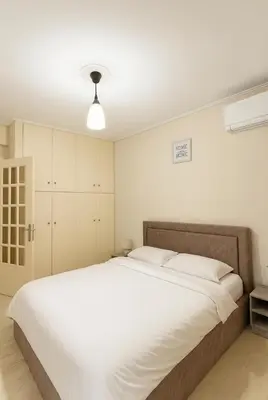 a bedroom with a large bed with white sheets at Mamour Apartments, Near Tram & 8' to Beach, Queen Bed Comfort in Athens