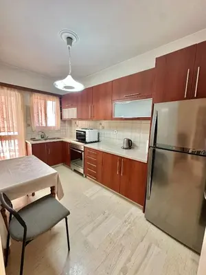 a kitchen with wooden cabinets and a stainless steel refrigerator at Mamour Apartments, Near Tram & 8' to Beach, Queen Bed Comfort in Athens