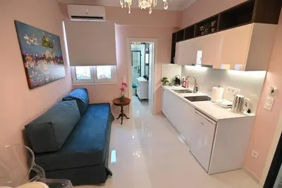 a living room with a blue couch and a kitchen at Warm & cozy studio - apartment 2 in Athens
