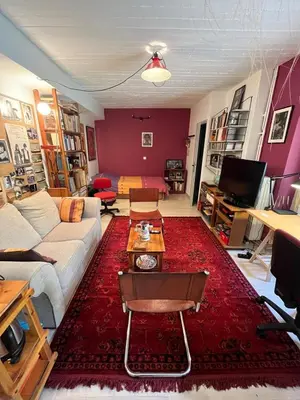 a living room with a white couch and a red rug at Cozy quiet studio near the sea in Athens