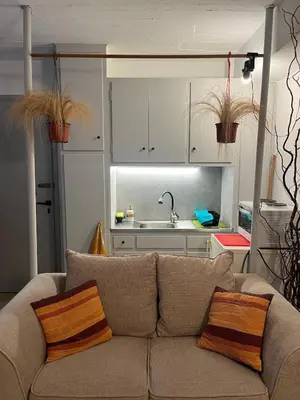 a living room with a couch and a kitchen at Cozy quiet studio near the sea in Athens